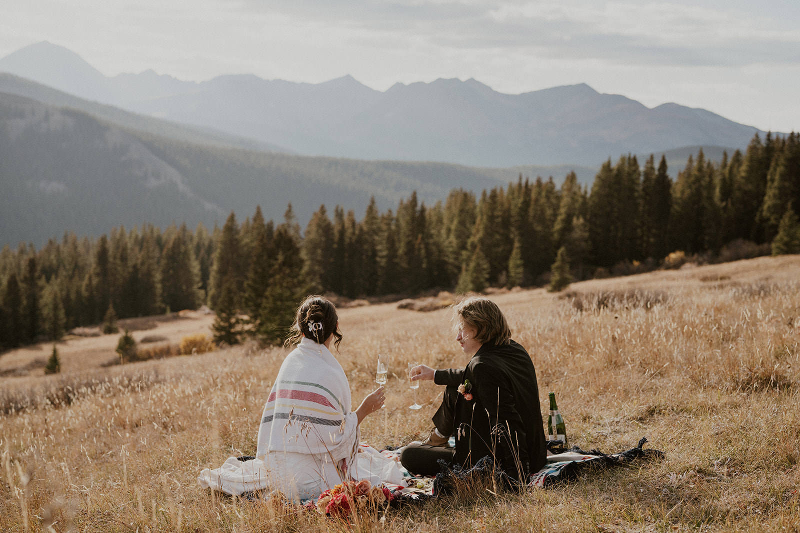 Bride and groom sipping champagne during their elopement picnic in the mountains