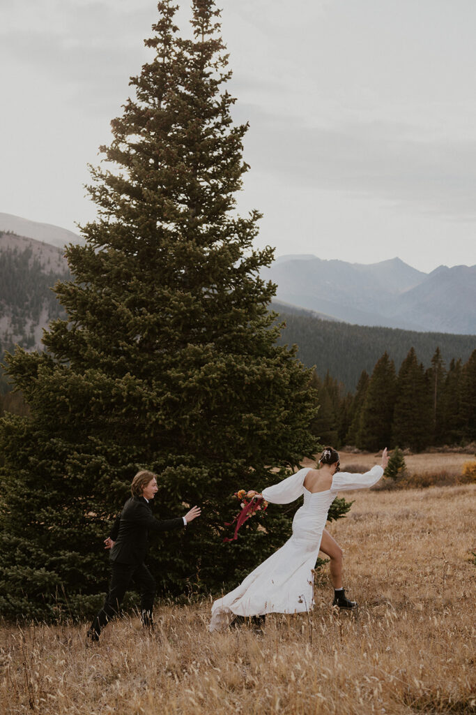 Bride and groom running through the mountains at Boreas Pass