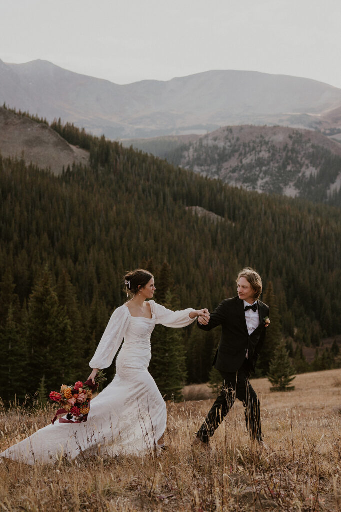 Bride and groom running through the mountains at Boreas Pass