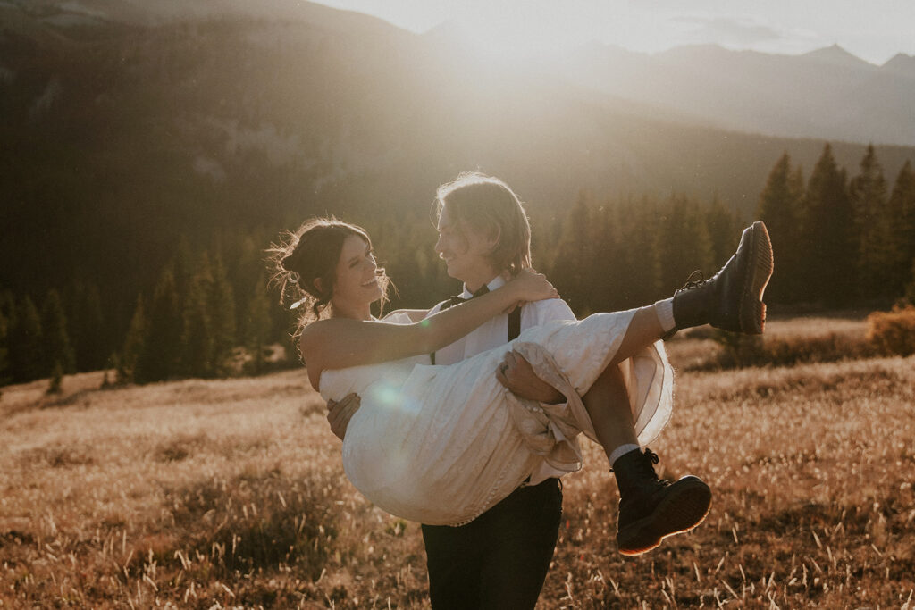 Groom picking up his bride during their sunset mountain elopement in Breckenridge 