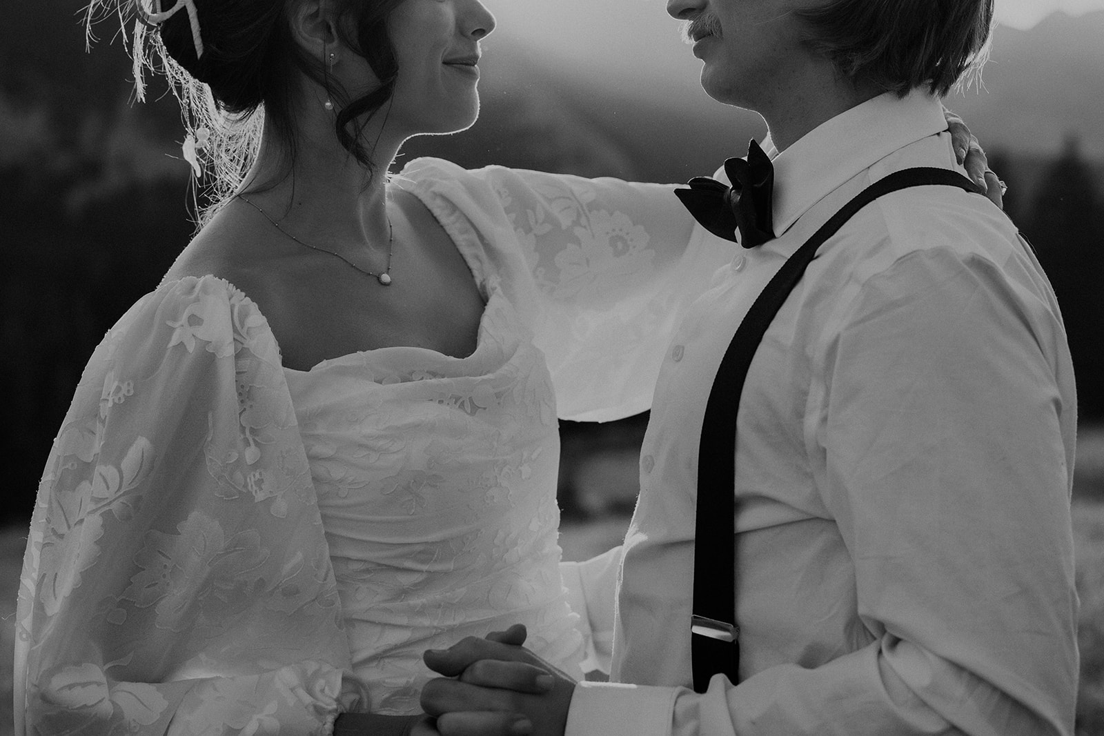 Black and white photo of a bride and groom holding hands in the mountains