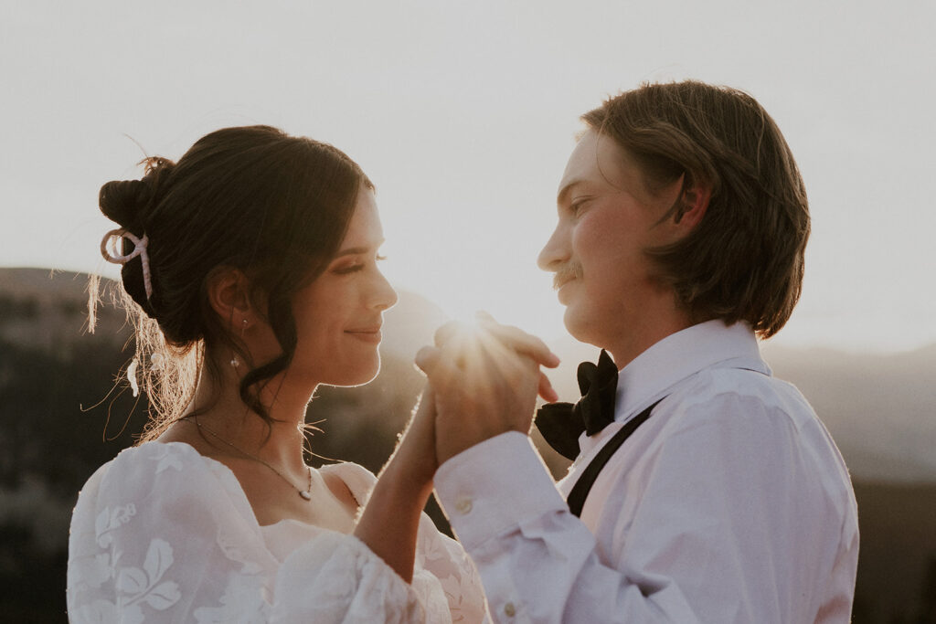 Bride and groom holding hands during sunset in the mountains