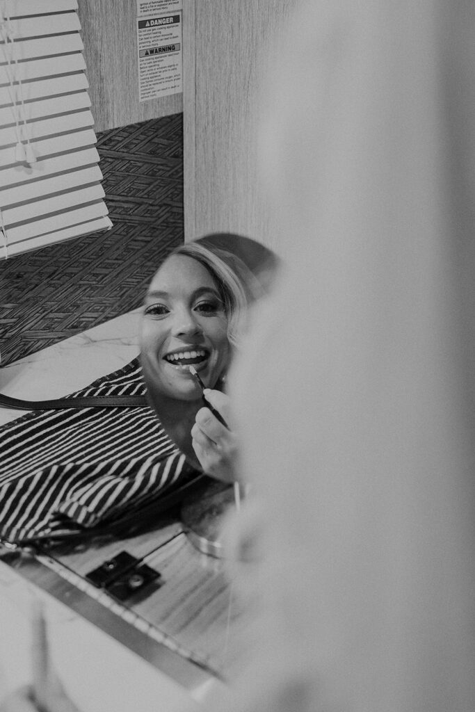 Black and white photo of a bride putting lipstick on