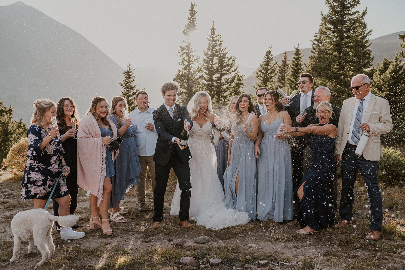 Bride and groom popping champagne with their friends and family