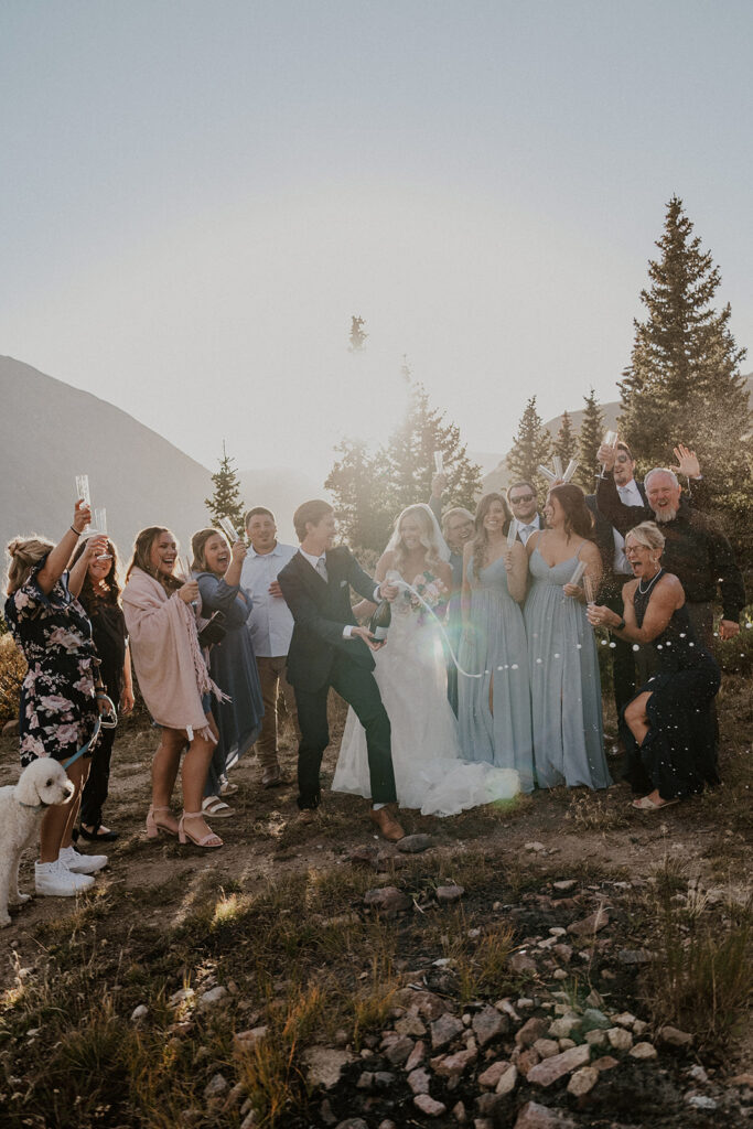 Bride and groom popping champagne with their friends and family