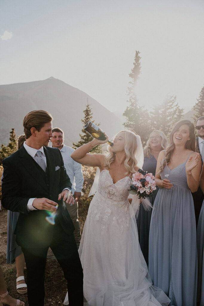 Bride drinking straight from the bottle of champagne