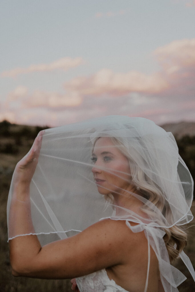 Bride posing under her veil in the Colorado mountains