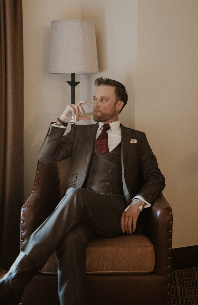 Indoor grooms portraits while he sips on a drink