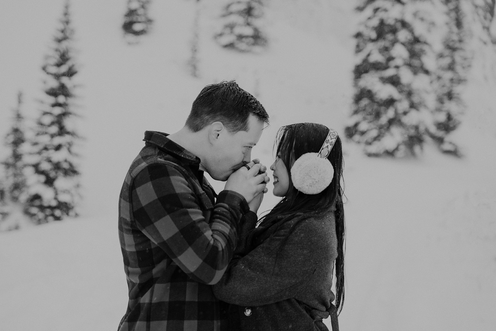 Black and white photo of a couple warming their hands during their snowy Colorado photoshoot in Boreas Pass