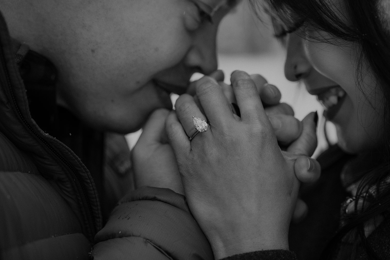 Black and white photo of a man and woman warming their hands during their winter Colorado photoshoot