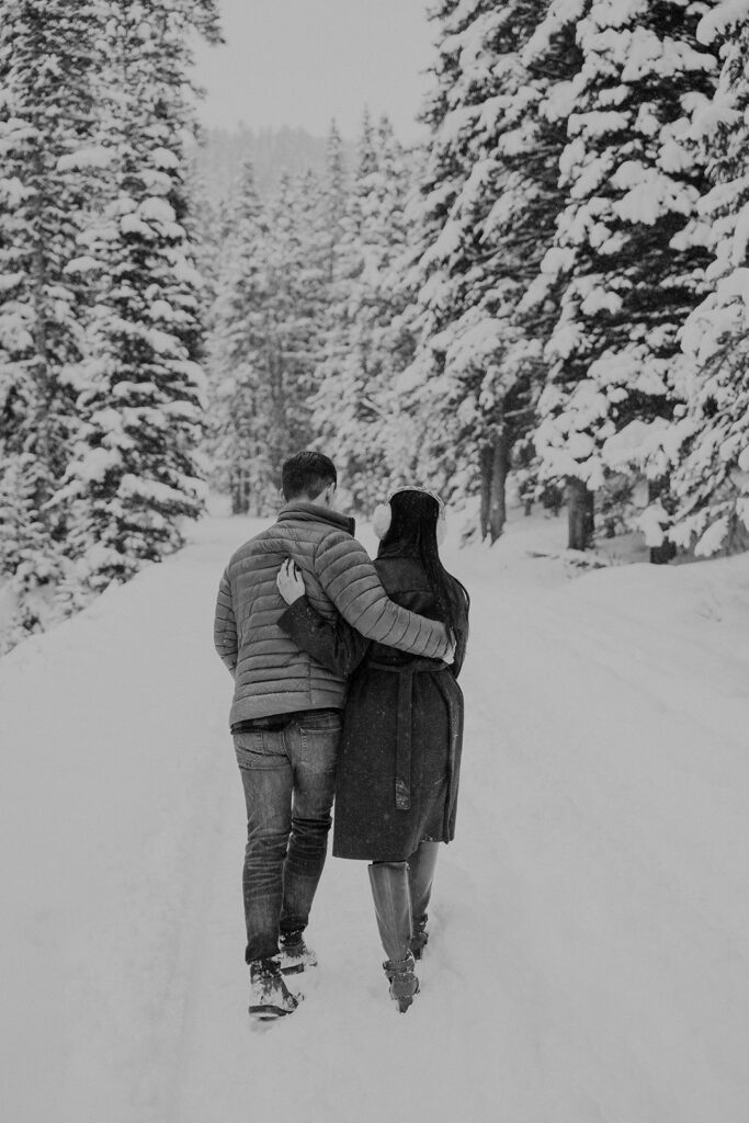 Black and white photo of a couple walking in the snow during their Boreas Pass engagement in Colorado