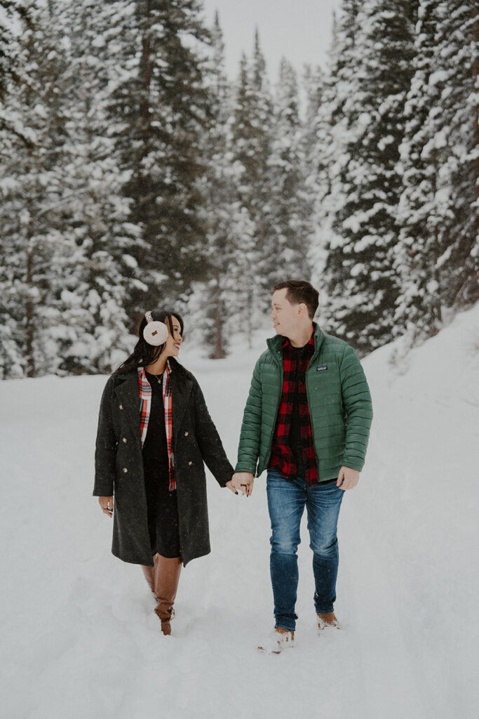 Man and woman walking in the snow for their winter Colorado photoshoot