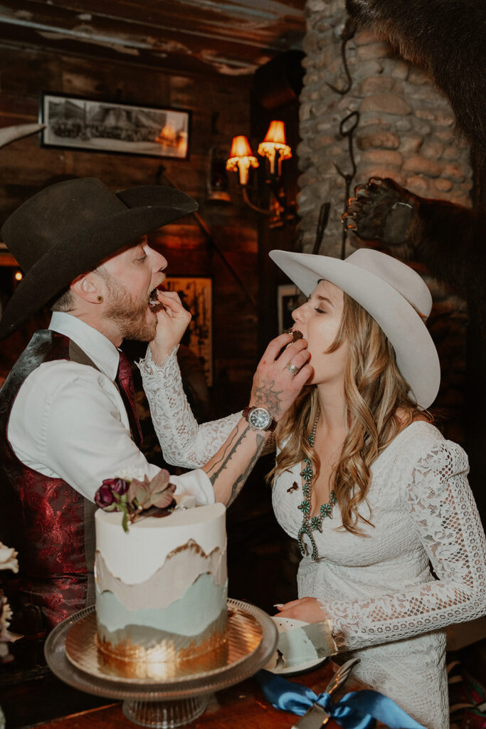 Bride and groom feeding each other their wedding cake during their intimate reception at Woody Creek Tavern