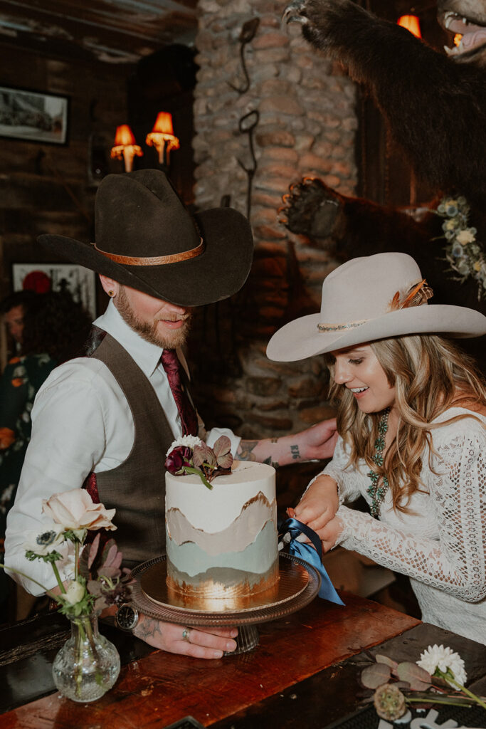 Bride and groom cutting into their wedding cake during their intimate reception at Woody Creek Tavern